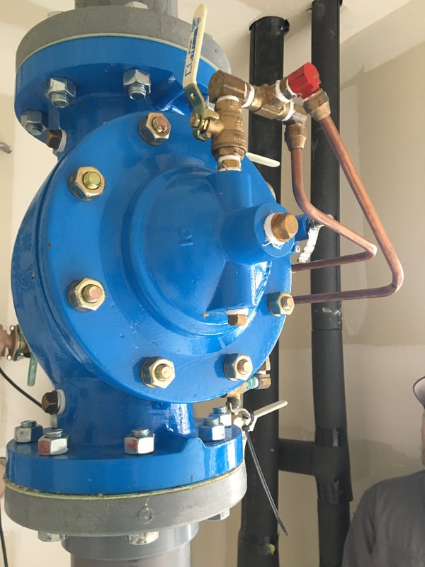 Blue mechanical valve with copper pipes and fittings attached, installed in a plumbing system, showcasing essential plumbing infrastructure.