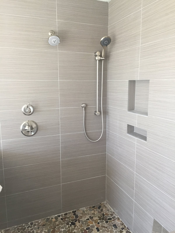 Modern shower featuring sleek gray tiles, a rainfall showerhead, and a handheld option, installed through our plumbing service in Georgetown, TX. Call today for expert upgrades.