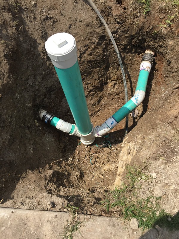 A newly installed drainage pipe system in a shallow excavation, featuring a vertical section and multiple horizontal connections, completed through our plumbing service in Georgetown, TX. Call today for fast, reliable service.